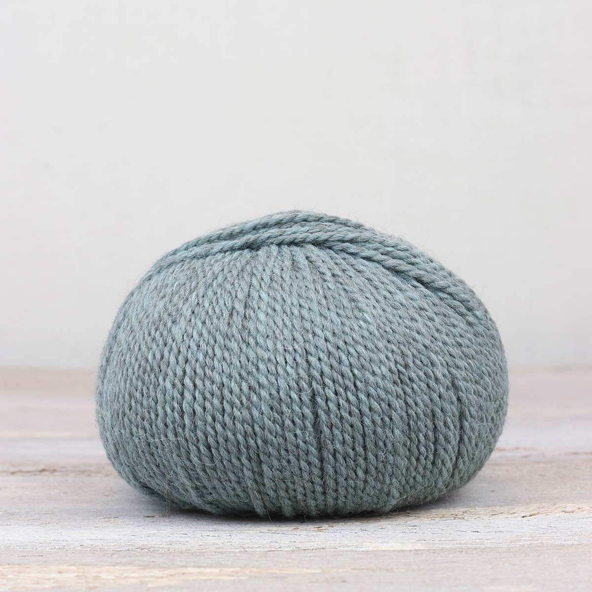 A single ball of The Fiber Co. &Make Aran in color Aqua