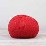 A single ball of The Fiber Co. &Make Aran in color Hot Like Me