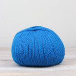 A single ball of The Fiber Co. &Make Aran in color Hyper Blue