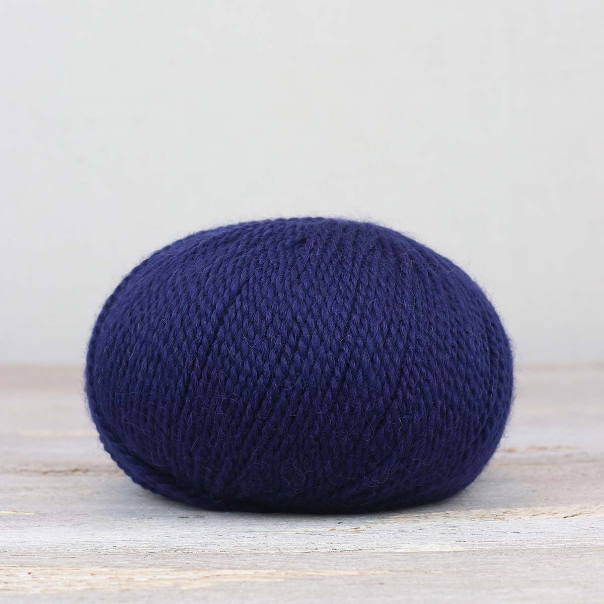 A single ball of The Fiber Co. &Make Aran in color Indigo Child