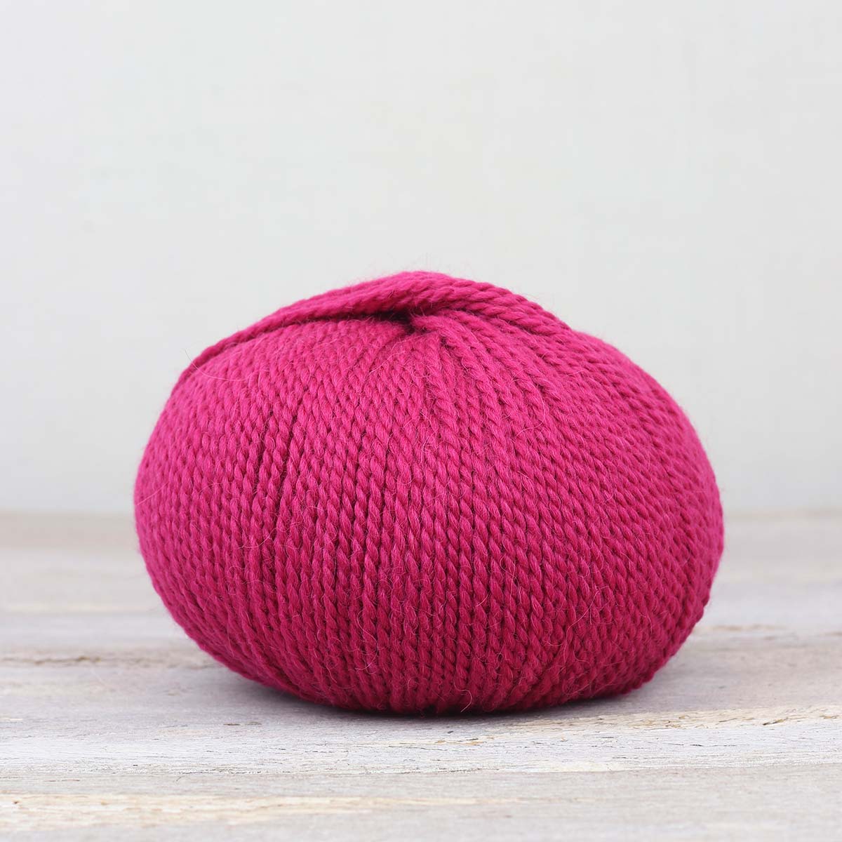 A single ball of The Fiber Co. &Make Aran in color Mille Pink