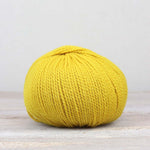 A single ball of The Fiber Co. &Make Aran in color Smiley