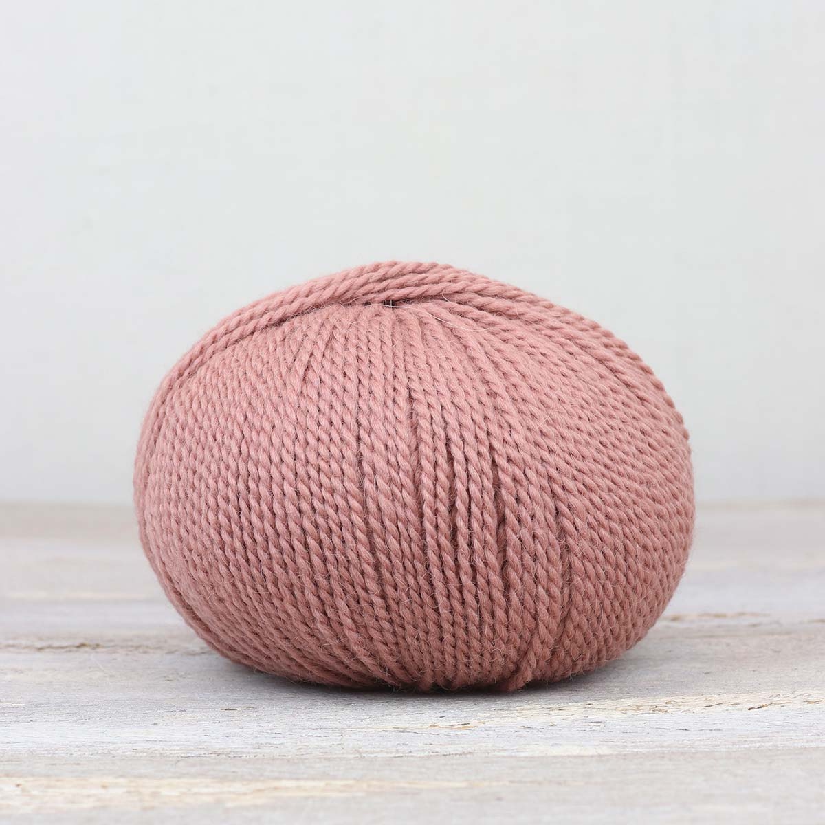 A single ball of The Fiber Co. &Make Aran in color Soft Love